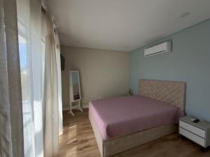 a bedroom with a pink bed and a window at Vila Grafenola in Montargil