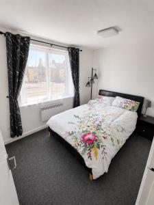 a bedroom with a bed with a floral comforter and a window at Beautiful Double room in Peterborough