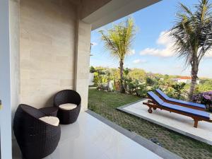 a patio with two chairs and a bench on a porch at Bunut Sari Guesthouse in Ungasan