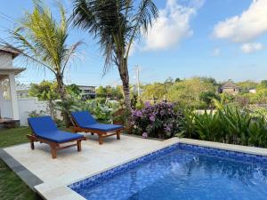 a swimming pool with two chairs next to a house at Bunut Sari Guesthouse in Ungasan