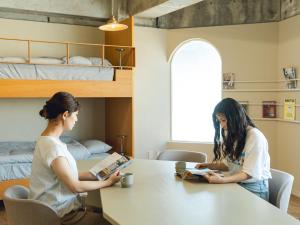 two women sitting at a table reading books at By The Tree Room in Amami