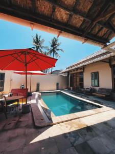 a swimming pool with a red umbrella and a table at La Boheme Mini in Gili Trawangan