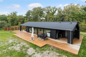 a house with a black roof and a wooden deck at 10036-Rorvig-Magevej-11 in Rørvig