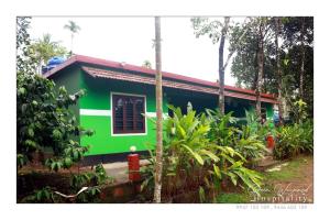 a green house with a red roof at Green wayanad homestay in Kenichira