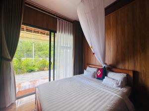 a bedroom with a bed and a large window at Son House in Dong Hoi