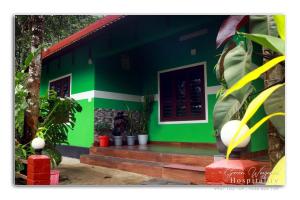 a green house with a bench in front of it at Green wayanad homestay in Kenichira +5 photos