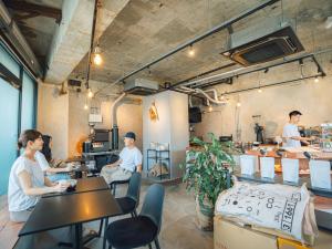 a group of people sitting at tables in a restaurant at By The Tree Room in Amami