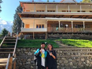 a man and a woman standing in front of a house at Fairy Meadows Comfort Lodges in Tato