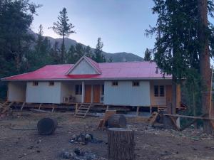 a house with a red roof in the woods at Fairy Meadows Comfort Lodges in Tato