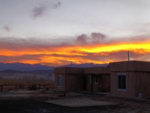 a building with a sunset in the background at Complejo El Mirador in Calingasta +6 photos