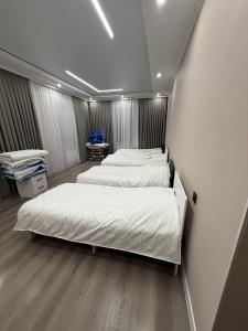 two beds in a room with white walls and wooden floors at Гостевой дом БАЯН in Cholpon-Ata