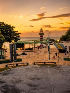 a sunset over a pier with a lighthouse and the ocean at Villa Penelope in Paracuru