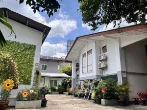 a white building with flowers and plants in front of it at Magic Garden Residence Bangkok in Bangkok