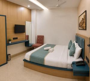 a bedroom with a bed and a chair and a television at New Skyrooms in Varanasi