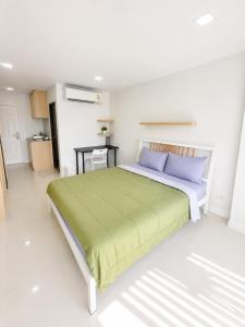 a white bedroom with a large bed with blue pillows at Peaberry Place - พีเบอร์รี่เพลส in Ban Zong Katiam