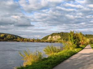 a path next to a river with trees and clouds at Einzelzimmer in Kelheim