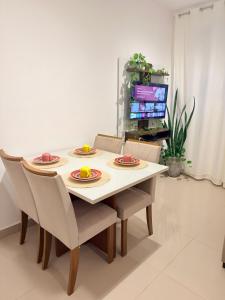 a dining room table with four chairs and a television at Auréa Residência - a 500 m da Praia in Cabedelo