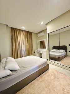 a bedroom with a large bed and a large mirror at منتجع لوريت in Qaryat at Ta‘mīr as Siyāḩīyah +11 photos