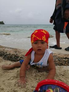 a baby playing in the sand on the beach at Isla Ganirdub in Río Azúcar