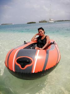 a woman is riding on an orange and gray raft in the water at Isla Ganirdub in Río Azúcar