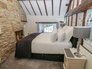 a bedroom with a bed and a stone wall at Lydgate Cottage in Eyam