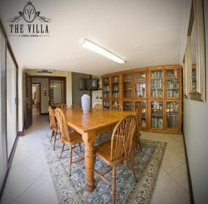 una sala da pranzo con tavolo e sedie in legno di The Villa Umhlanga a Durban