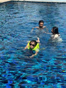 three people are swimming in a swimming pool at Bà Đen Garden - Hương Sen Quán in Tây Ninh