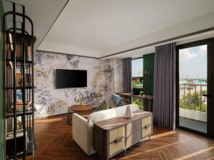 a living room with a white couch and a tv at Elais by ARTOTEL in Medan