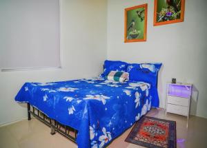 a bedroom with a bed with a blue comforter at Cabinas Los Colibris in Pocosol