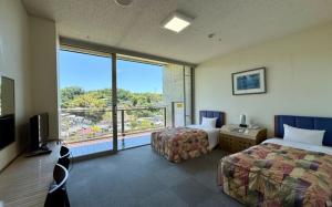 a hotel room with two beds and a large window at WELLNESS PARK IWAKI Iwaki Yuttarikan in Iwaki