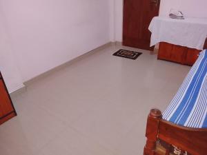 a room with a white floor with a bed and a table at TRAVAL dksr in Anuradhapura +1 photo