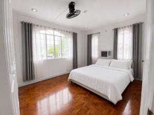 a white bedroom with a large white bed and windows at Trip Nest Homestay in Manila