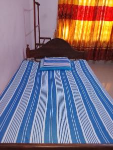 a bed with blue and white striped sheets in a room at TRAVAL dksr in Anuradhapura