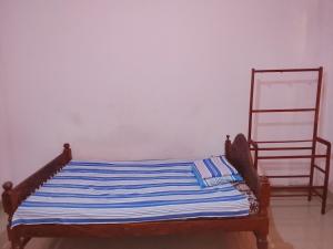 a bed with a blue and white striped blanket on it at TRAVAL dksr in Anuradhapura