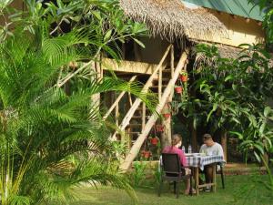 two people sitting at a table in front of a hut at Sigiri Veenus Tree House in Sigiriya