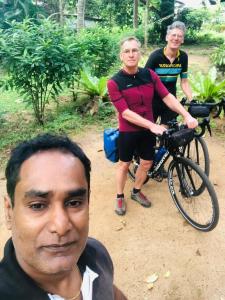 two men are standing next to a bike at Sigiri Veenus Tree House in Sigiriya