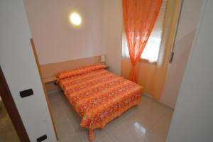 łóżko w pokoju z pomarańczowym kocem w obiekcie Riva Beach Apartment w mieście Riva Ligure