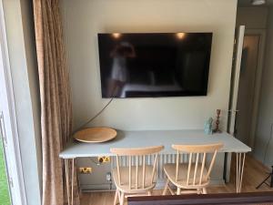 a table with two chairs and a television on a wall at The Warwick Room in Warwick