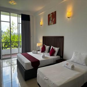 a hotel room with two beds and a balcony at Kandy Hub Guest House in Kandy