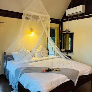 a bedroom with a bed with a net on it at Netnatee Amphawa in Ban Plai Khlong Om