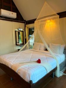 a bedroom with a bed with a canopy at Netnatee Amphawa in Ban Plai Khlong Om