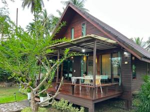 a house with a deck with a table and chairs at Netnatee Amphawa in Ban Plai Khlong Om