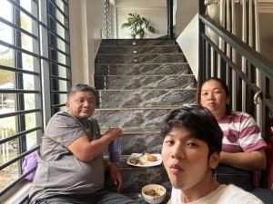 a group of three people sitting on a staircase at The Y Shop in Phumĭ Bŏs Tarĕt