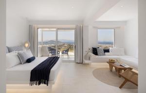 a white bedroom with a large bed and a living room at Paradisia Suites in Naxos Chora