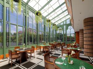 a restaurant with tables and chairs and windows at Elais by ARTOTEL in Medan