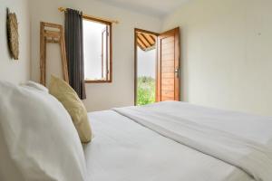 a white bed in a room with a window at Bee Camp Bedugul by AGATA in Bedugul