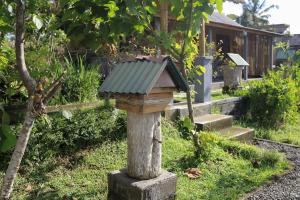 a bird house sitting on a stump in a garden at Bee Camp Bedugul by AGATA in Bedugul +11 photos