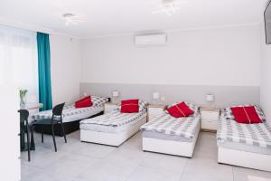 a room with four beds with red pillows at Motel Witnica in Witnica