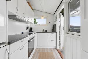 a kitchen with white cabinets and a window at Nordic Style Summer House For Two in Bogense