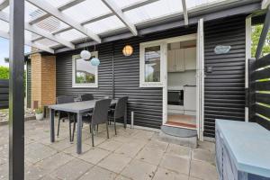 a patio with a table and chairs and a pergola at Nordic Style Summer House For Two in Bogense